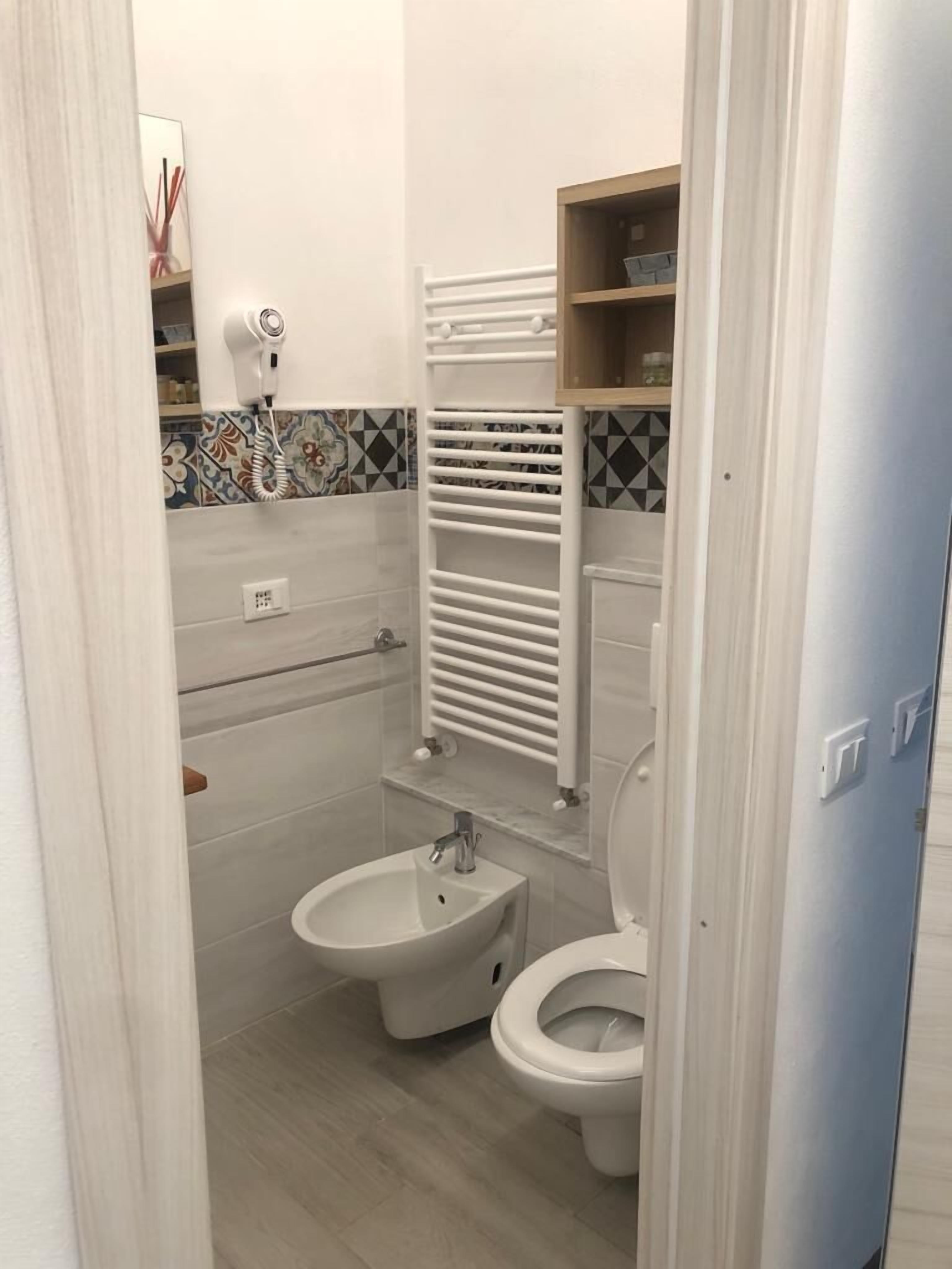 Un baño pequeño con bidé, inodoro y perchero para toallas.