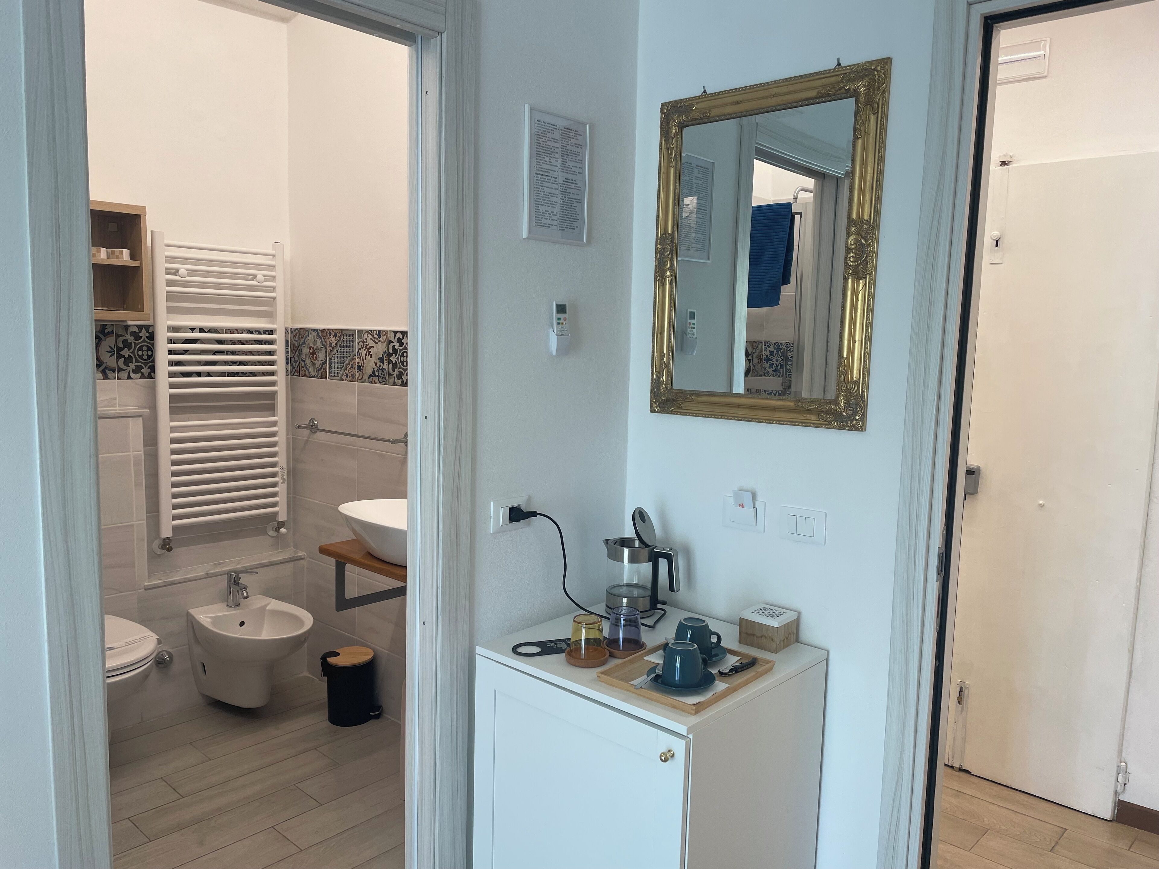 Un baño con inodoro, bidé, lavabo y espejo con marco dorado.