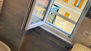 A bathroom with a window, a toilet, and a sink.