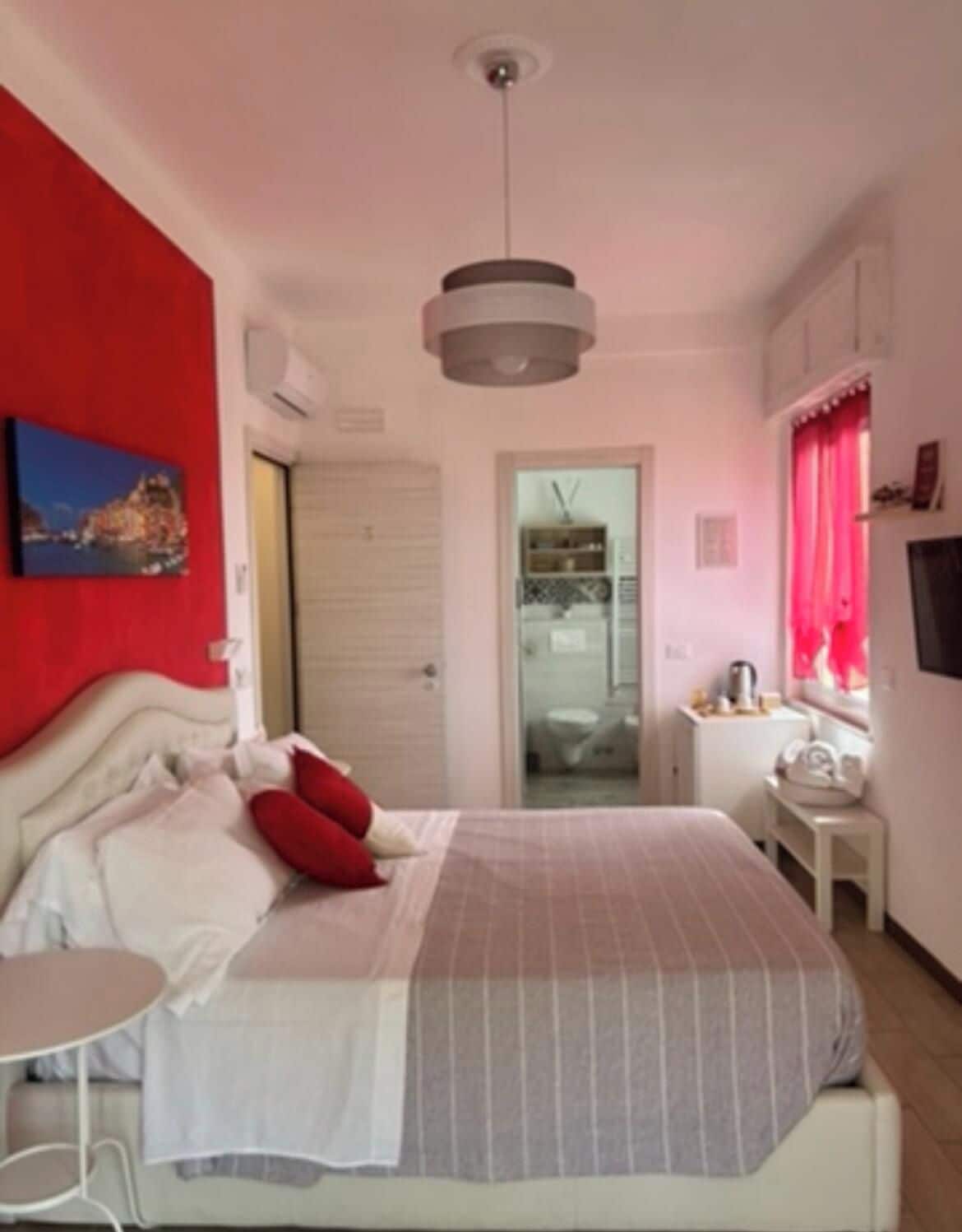 A bedroom with a bed, bedside table, and a red wall.