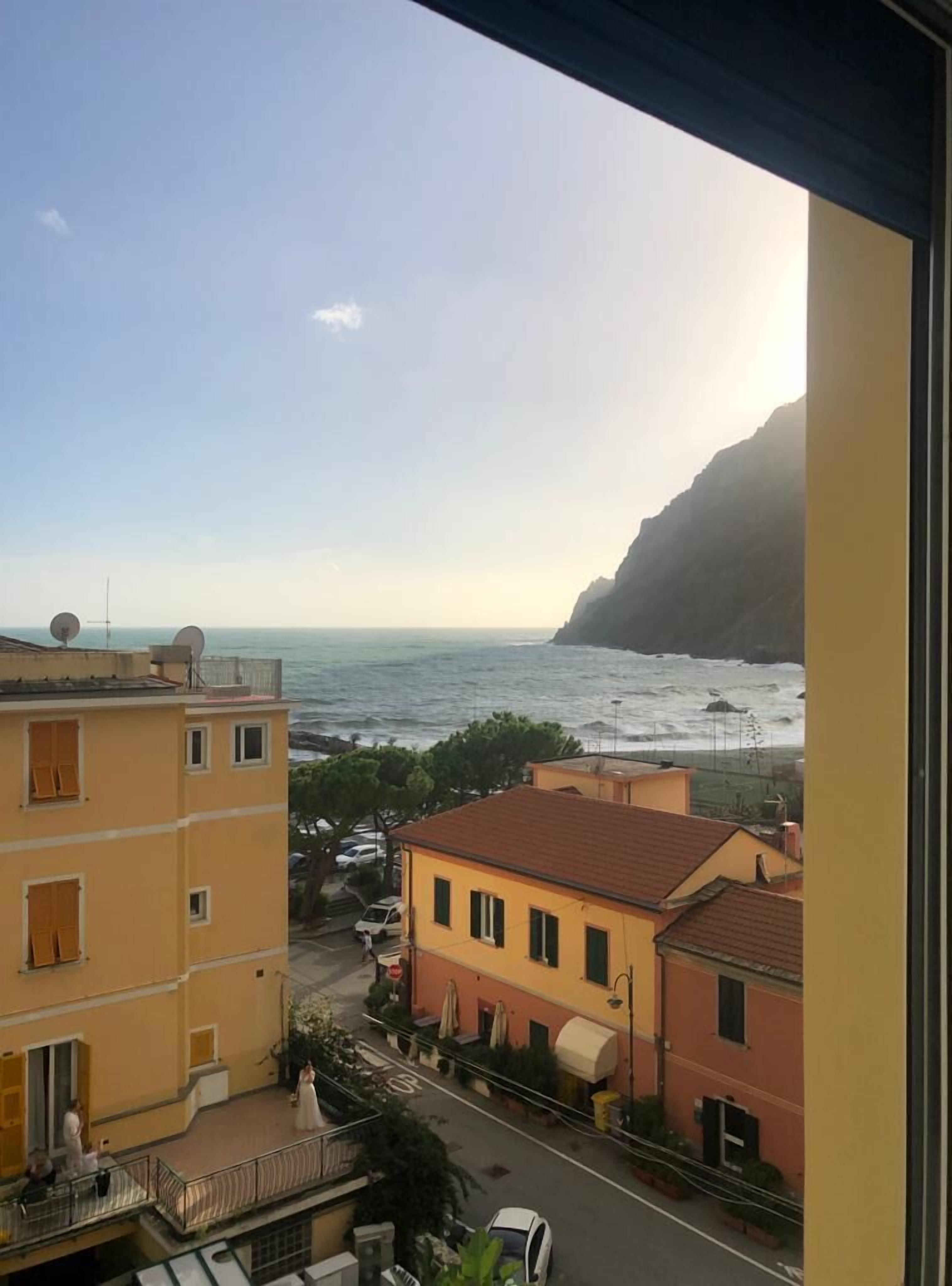Une vue sur la côte depuis un balcon, avec des bâtiments au premier plan et une falaise rocheuse en arrière-plan.