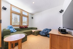 Una sala de estar moderna con un sofá modular, una mesita redonda, un sillón informal y un televisor de pantalla plana.