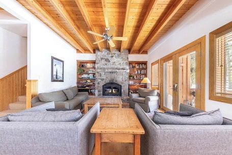 A living room with a stone fireplace, wooden ceiling beams, and a ceiling fan.. Chalet Town Home 05 - Beautiful Townhome nestled in the California's Sierra