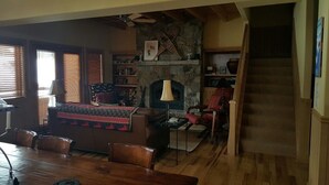 Un salon chaleureux avec une cheminée, des meubles en bois et un escalier menant à un autre niveau.