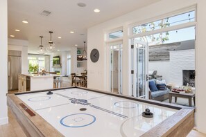 A modern interior with a shuffleboard table, a dining area, and a fireplace. - Stunning 5bdr Minutes to Beach, Pier, Restaurants Emerald Cove by Avantstay (Newport Beach)