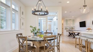 A dining area with a round table, wooden chairs, and a chandelier. - Stunning 5bdr Minutes to Beach, Pier, Restaurants Emerald Cove by Avantstay (Newport Beach)