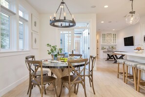 A dining area with a round table, wooden chairs, and a chandelier. - Stunning 5bdr Minutes to Beach, Pier, Restaurants Emerald Cove by Avantstay (Newport Beach)