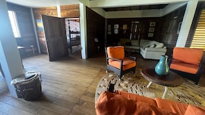 A cozy living room with a wooden floor, a sofa, a chair, and a coffee table. - Private wooden villa with stunning ocean views, in an enchanting garden setting. (Salybia Kalinago Territory)