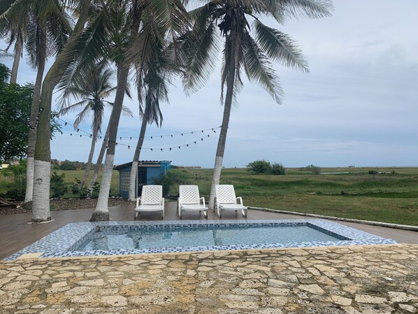 Un área de piscina con sillas de descanso y palmeras.