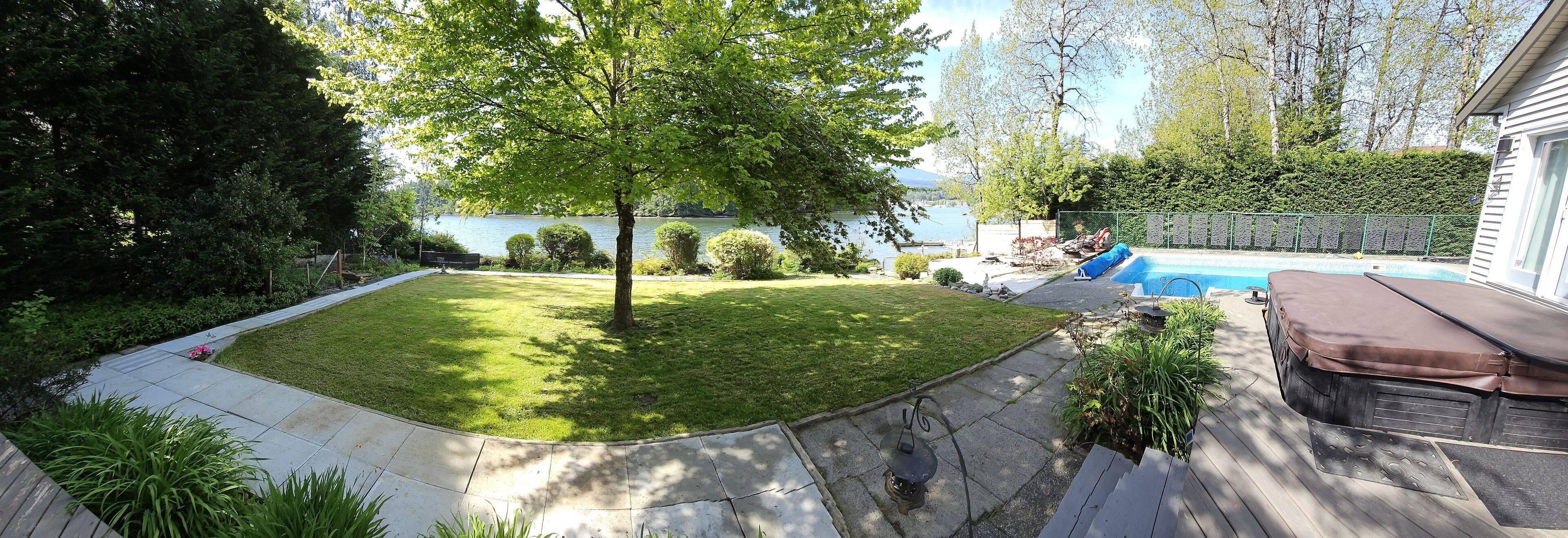 A backyard with a swimming pool, a hot tub, and a wooden deck.