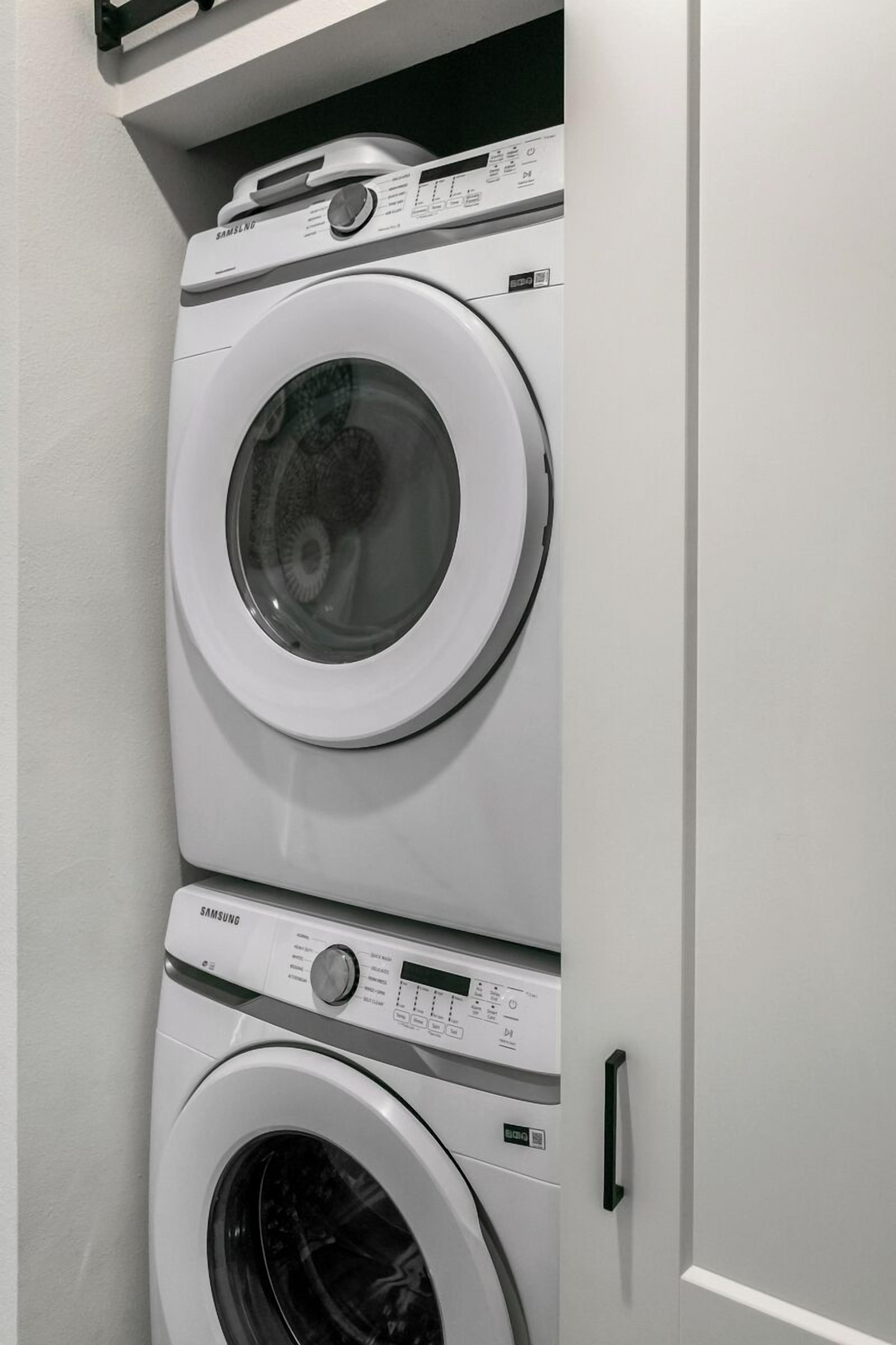 A stacked washer and dryer unit with a control panel and a door handle.