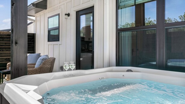 A hot tub in a covered outdoor area with a view of the house and a wooden fence. - Rise & Wine | Hot Tub | Sleeps 4 (Fredericksburg)