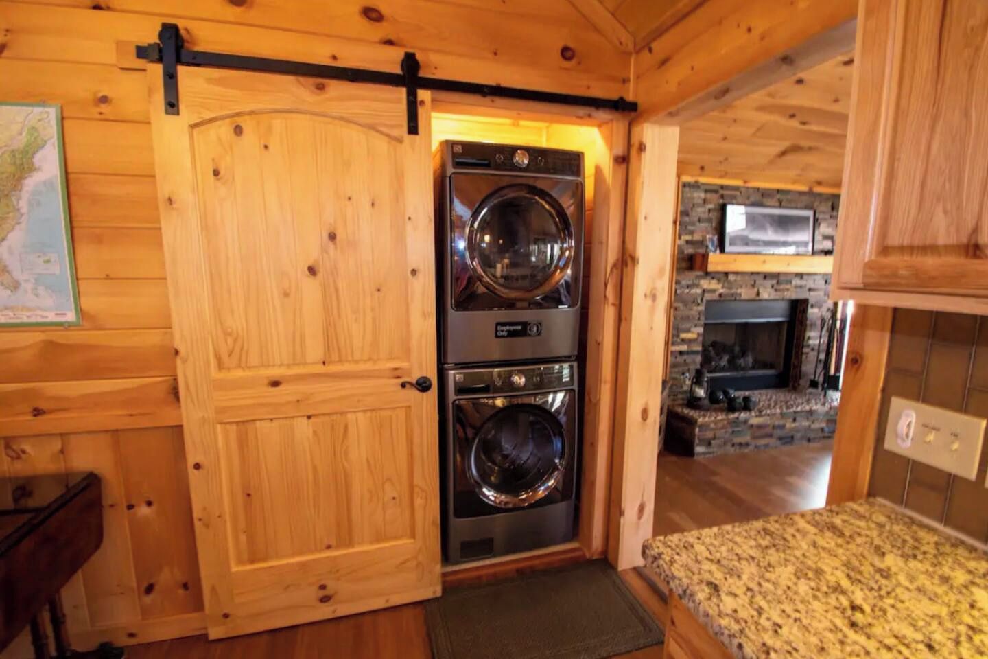 A wooden interior with a laundry room featuring stacked washers and dryers.