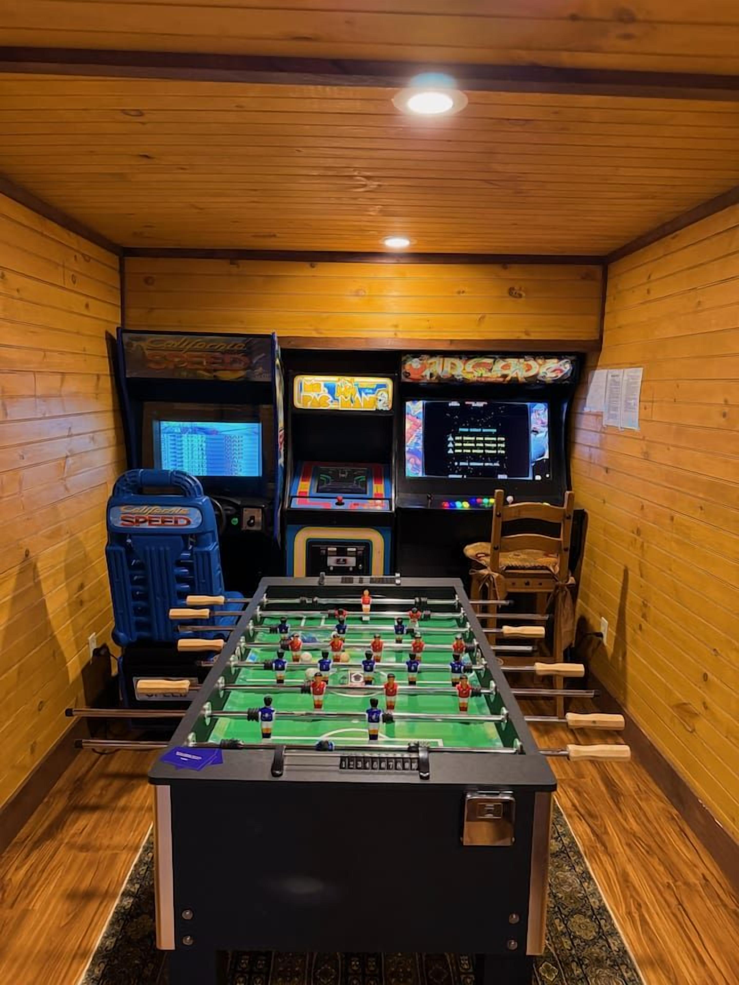 Ein Raum mit einem Kicker, zwei Spielautomaten und einem Holzbstuhl.