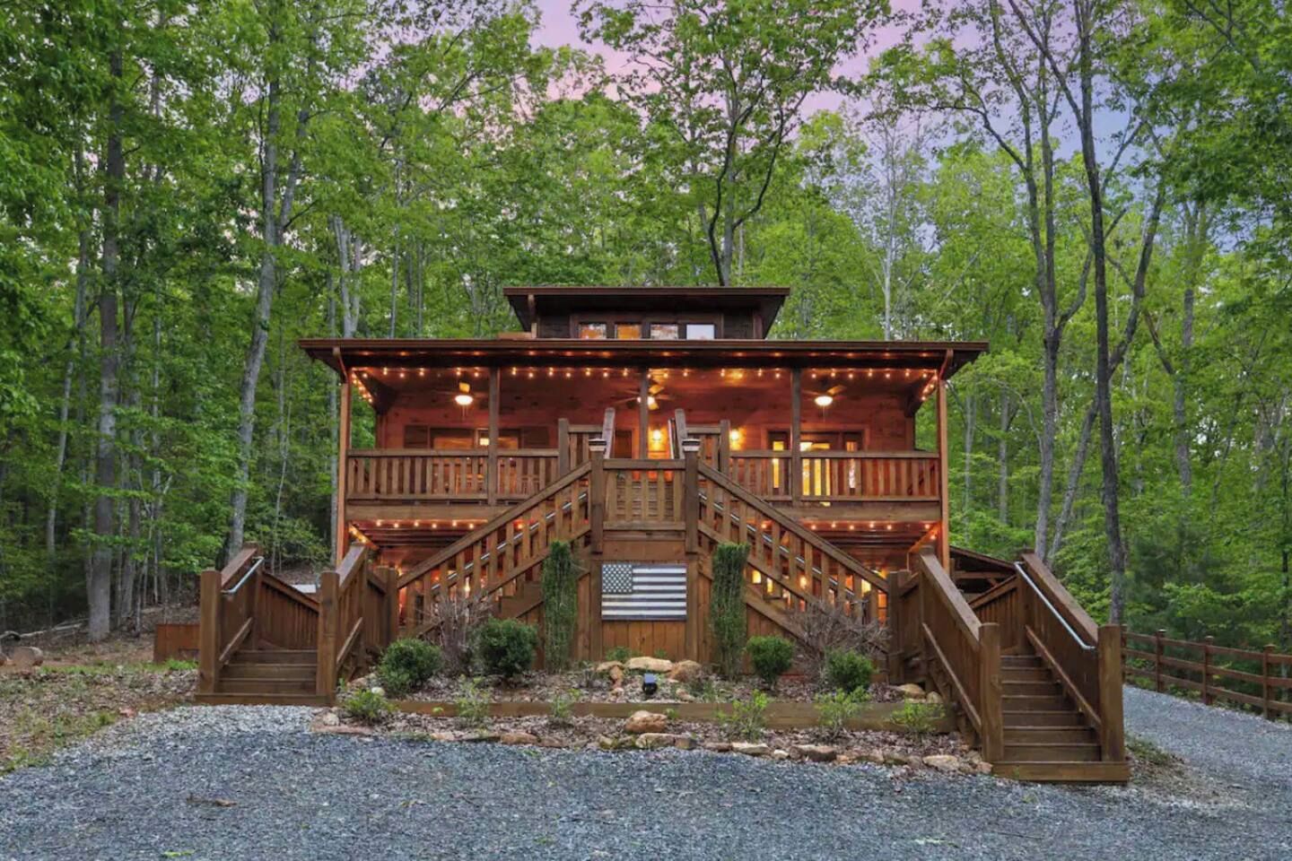 A wooden cabin with a porch, stairs, and string lights.