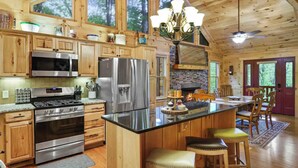 Una cocina amplia con armarios de madera, electrodomésticos de acero inoxidable, una isla grande y una zona de comedor con sillas de madera.