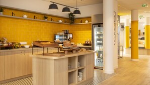 Un área de cocina moderna con pared de ladrillo amarillo, gabinetes de madera e isla central con estación de café.