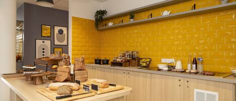 Een keuken met een houten aanrecht, een achterwand van gele bakstenen en diverse keukenapparatuur en keukengerei.