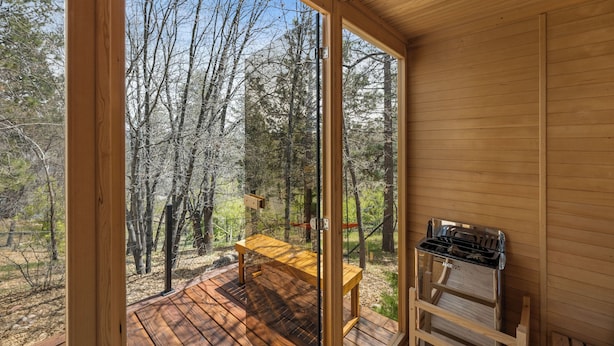 Una baita di legno con una veranda, un tavolo e un barbecue.
