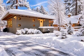 A snow-covered lodge with a wooden exterior, a covered porch, and a visible chimney. - Clerestory Cottage | Private Hot Tub, Sauna & Walk to Big Bear Lake (Big Bear Lake)
