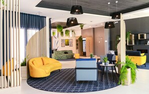 A modern lounge area with a yellow sofa, a blue patterned ottoman, and a black and white patterned rug. - T2 moderne, près de la gare | TV, bureau, wifi (Angers)
