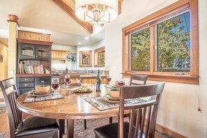 A dining area with a round table, chairs, and a window with a view of trees. - Creekside on Quigley - 3BD Private Home on trails + Hot Tub (Hailey)
