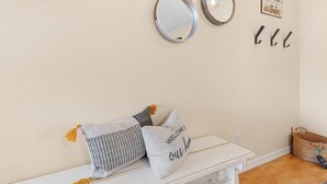 Een kamer met een witte bank, twee kussens en spiegels aan de muur.