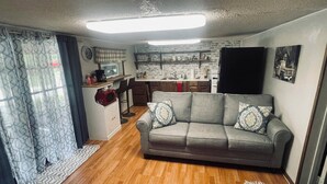 A compact living space with a kitchenette, a sofa, and a patterned rug.