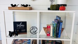 Une étagère blanche contenant des livres, une enseigne et des objets décoratifs.