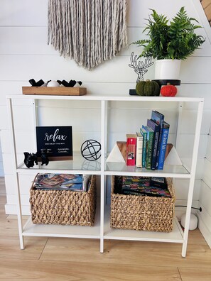 A white shelving unit with books, a sign, and decorative items. - Cozy Private A-Frame Retreat /Hot Tub/w-Views (Monument)