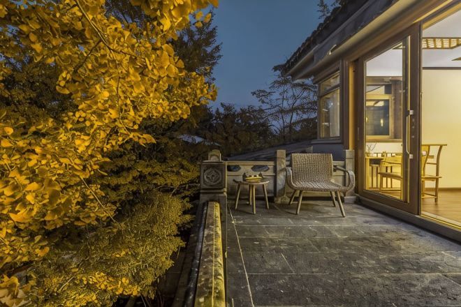 Un patio con una mesa y sillas, una mesita decorativa y un ventanal de vidrio que da a un espacio interior con una mesa de comedor.