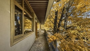 A corridor with windows and a view of trees with yellow leaves. - First Sight Boutique Cottage (Tengchong)