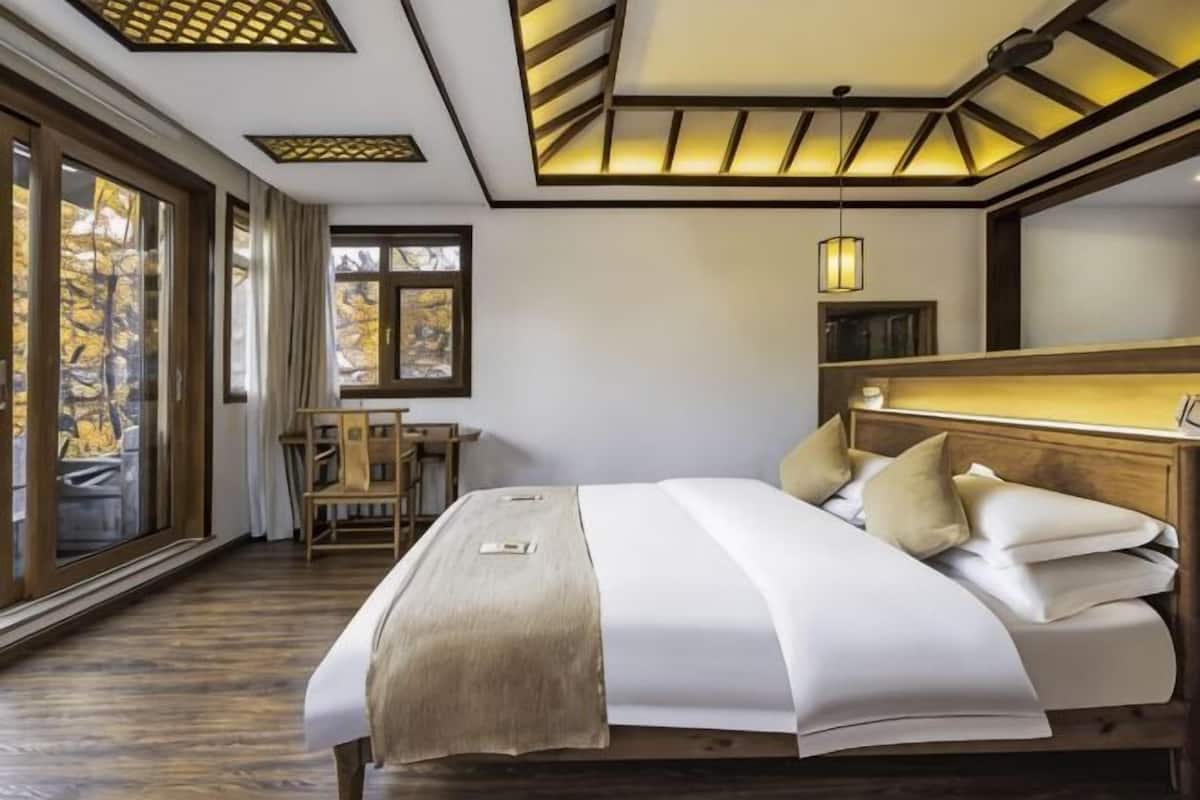 A bedroom with a large bed, a desk, and a window with a view.