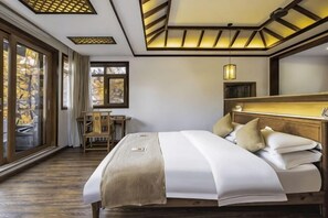 A bedroom with a large bed, a desk, and a window with a view. - First Sight Boutique Cottage (Tengchong)