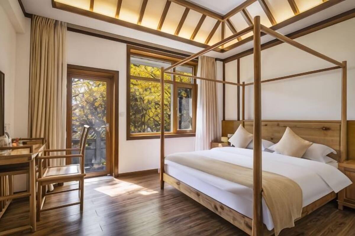 A room with a four-poster bed, a desk, and a chair.
