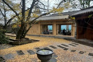 A traditional building with a tiled courtyard, a large tree, and a water feature. - First Sight Boutique Cottage (Tengchong)