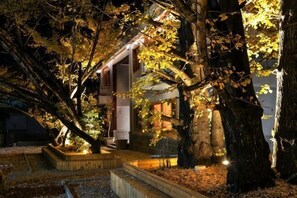 A building with a staircase leading to a door, surrounded by trees and illuminated by warm lighting. - First Sight Boutique Cottage (Tengchong)