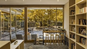 A modern interior with a glass wall, a wooden desk, bar stools, and a bookshelf. - First Sight Boutique Cottage (Tengchong)