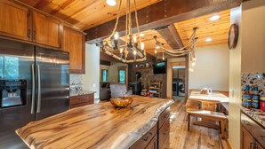 Une cuisine moderne dotée d’un grand îlot central, d’appareils électroménagers en acier inoxydable et d’un plafond en bois rustique.
