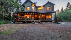 Une maison à deux étages avec un porche, entourée d’arbres.