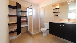 Un baño moderno con cabina de ducha, inodoro y estantes empotrados.