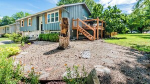 A two-story house with a front porch, a wooden staircase, and a gravel driveway. - Tailgate House Near Stadium! Fire pit, basketball ct, pool table! Cozy and fun! (Manhattan)