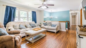 A living room with two sofas, a coffee table, and a ceiling fan. - Tailgate House Near Stadium! Fire pit, basketball ct, pool table! Cozy and fun! (Manhattan)