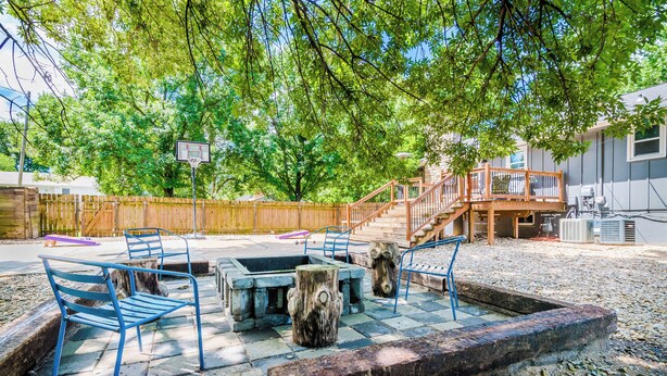 An outdoor patio with a fire pit, seating, and a basketball hoop. - Tailgate House Near Stadium! Fire pit, basketball ct, pool table! Cozy and fun! (Manhattan)