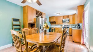 A kitchen with wooden cabinets, a dining table, and chairs. - Tailgate House Near Stadium! Fire pit, basketball ct, pool table! Cozy and fun! (Manhattan)