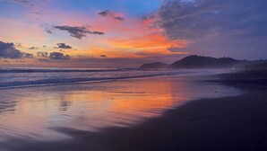 A beach at sunset with calm waves and distant hills. - Gorgeous 3 floor ocean front home. Private gated community. South Beach, Jaco!  (Jacó)