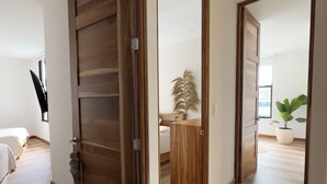A room with a wooden door, a white rug, and a plant. - Gorgeous 3 floor ocean front home. Private gated community. South Beach, Jaco!  (Jacó)
