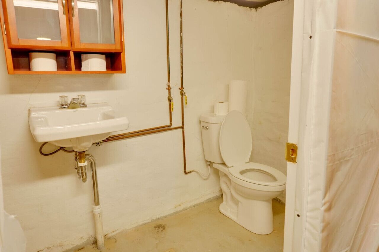 Un baño con lavamanos blanco, inodoro y armario de madera sobre el lavamanos.