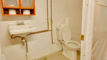 Un baño con lavamanos blanco, inodoro y armario de madera sobre el lavamanos.