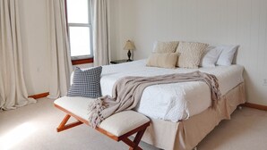 Ein Schlafzimmer mit einem Bett, einer Sitzbank, einer Lampe und einem Fenster.